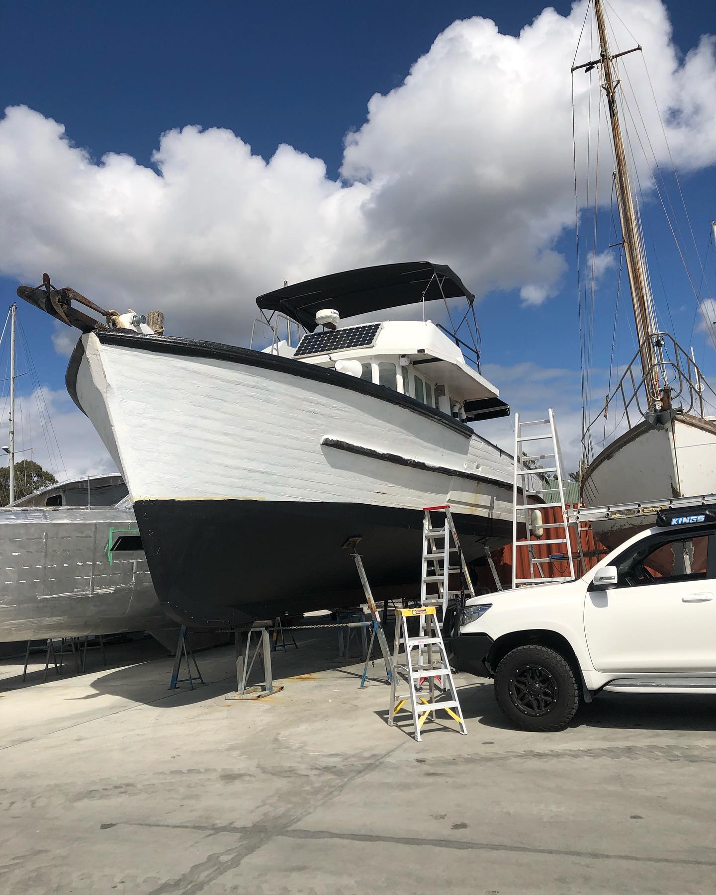 An old timber boat freshly painted white on the hardstand