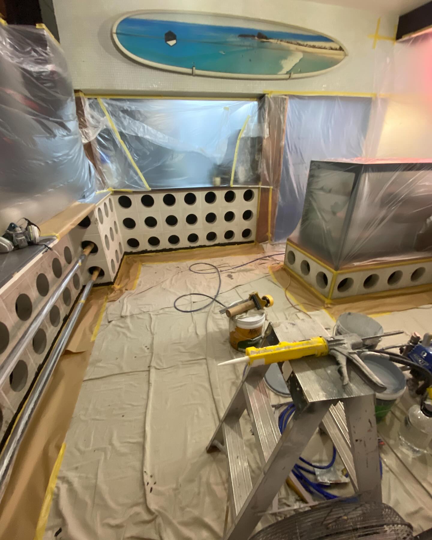 A shop fit-out with a painted breeze block wall and floor protected by drop sheets
