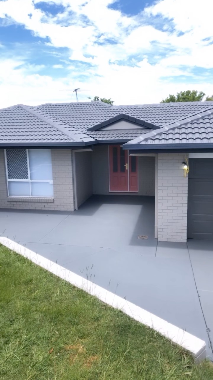 A brick home painted grey with a matching grey driveway